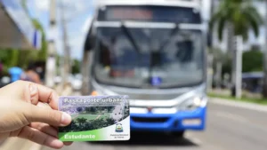 Imagem de alguém segurando uma carteira de vale transporte e um ônibus de Palmas ao fundo